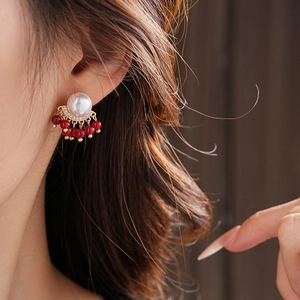 Detail of vintage tassel earrings featuring a white pearl and red bead fringe on model