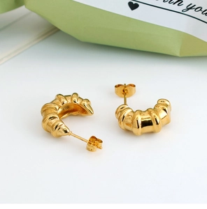 Detail of gold croissant hoop earrings with vintage texture and push-back closure