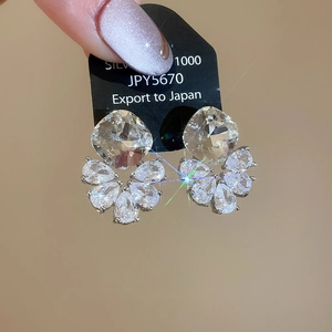 Detailed macro of silver zircon earrings featuring square and water-drop shaped stones