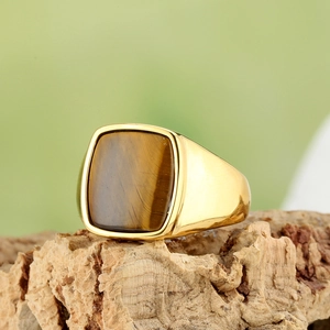Men's gold square tiger eye stone ring showcased on natural tree bark background