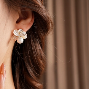 Gros plan de boucles d'oreilles fleurs avec pétales blancs et perles sur un modèle