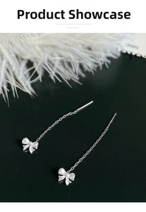 Detail of S999 sterling silver bow tassel earrings with matte finish on feathers background