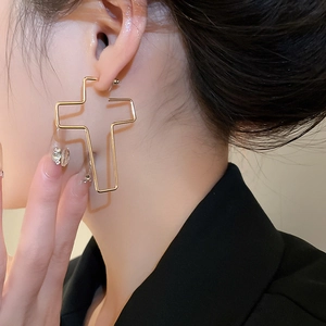 Vue macro de boucles d'oreilles créoles en forme de croix dorée avec finition polie et éclat