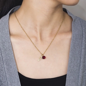 Close-up of golden tulip necklace with a red birthstone pendant on a female model