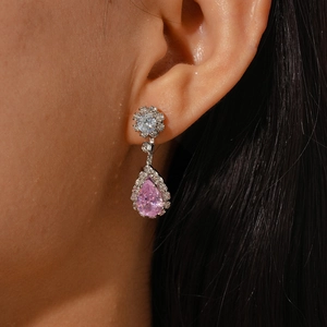Macro view of pink pear-shaped drop earrings with brilliant halo setting on ear
