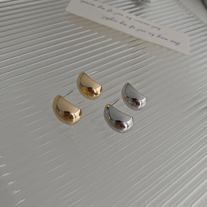 Close-up of gold and silver water drop stud earrings on a textured aesthetic background