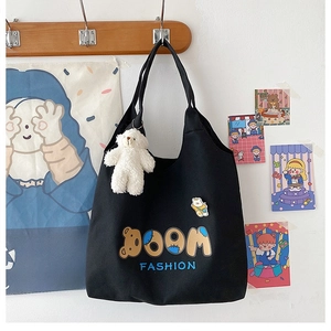 Detailansicht der schwarzen Segeltuch-Tasche mit BOOM-Grafik und Plüschbär-Anhänger