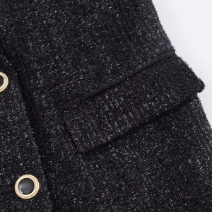 Makro-Detail der schwarzen Tweed-Jacke mit metallischem Silberfaden und goldenem Knopf