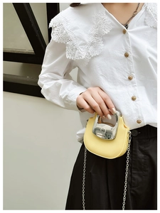 Close-up of yellow leather mini bag with distinctive silver metal handle and chain strap