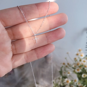 Close-up of a silver cross necklace featuring sparkling zircons on a delicate chain