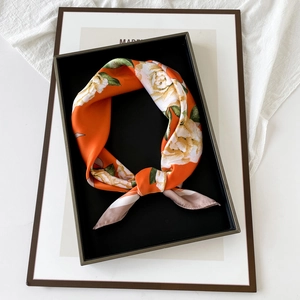 Elegant orange satin silk square scarf with floral print neatly folded in a black gift box