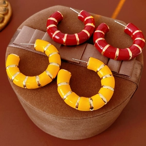 Macro shot of red and yellow enamel C-hoop earrings with gold-tone bamboo pattern
