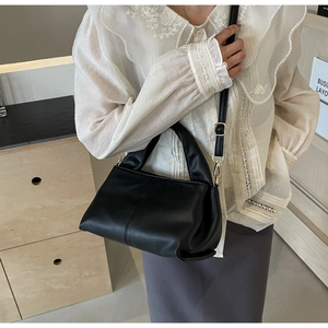 Detail of black pebbled leather texture and gold metal buckle on a stylish shoulder bag