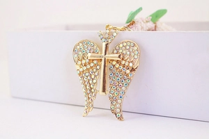 Macro shot of golden angel wing cross pendant with colorful rhinestones on box