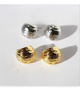 Macro shot of gold-plated brass C-shaped hoop earrings with hammered texture and cubic zirconia