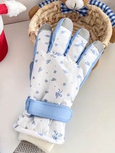 Detail of blue floral ski gloves showing adjustable velcro strap and knit cuffs