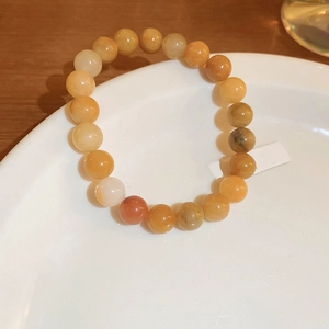 Detailed view of natural yellow agate beaded bracelet on a white ceramic plate