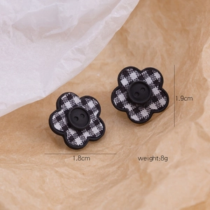 Detail view of black and white houndstooth flower earrings with size and weight specs