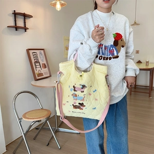 Detail of yellow quilted tote bag with cute cartoon dog embroidery and pink strap