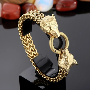 Detail of a bold gold stainless steel double wolf head bracelet with thick braided chain