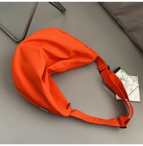 Detailed view of bright orange nylon crescent crossbody bag with adjustable strap