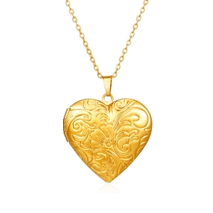 Dettaglio macro del medaglione a cuore dorato con incisioni a volute floreali