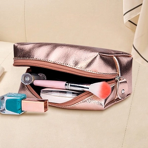 Rose gold PU leather makeup bag opened to reveal brushes and cosmetics on a soft sofa