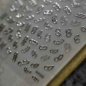 Macro shot of silver 3D metallic nail stickers featuring interlocking chain designs