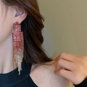 Close-up of geometric tassel earrings with gradient rhinestones on a female model