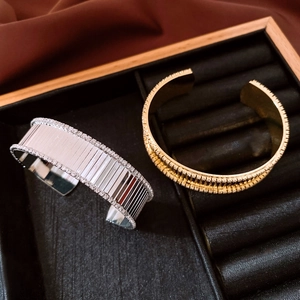 Dettaglio di bracciali a polsino placcati oro e argento con bordi in zirconi