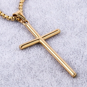 Macro shot of polished gold-finished stainless steel cross pendant on soft plush background