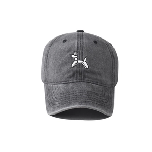 Detailed close-up of white balloon dog embroidery on washed dark grey denim baseball cap