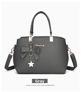 Detail of grey pebble leather handbag with floral pendant and detachable strap