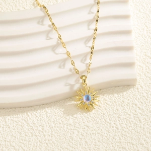 Golden sunburst pendant necklace with a blue iridescent stone and sparkling zircon accents