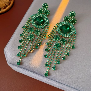 Dettaglio di orecchini pendenti vintage di lusso con cristalli verdi su velluto