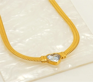 Detailed close-up of a gold-plated snake chain necklace with a blue heart-shaped zircon
