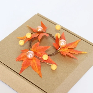 Detail of autumn napkin ring with orange maple leaves, berries, and pearls for Halloween