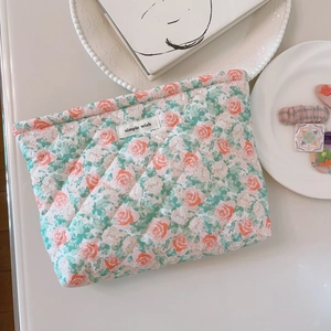 Floral quilted cotton makeup bag with green and pink patterns on a white desk