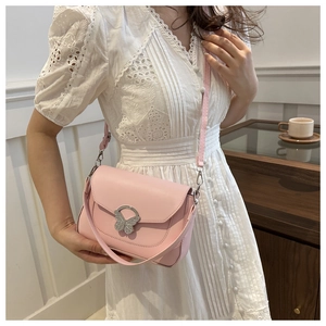 Close-up of pink shoulder bag with elegant butterfly metal clasp and stylish handle strap