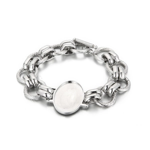 Macro detail of silver stainless steel chain bracelet with oval centerpiece and T-bar clasp