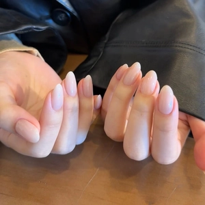 Natural nude almond press-on nails with glossy finish shown on hands in natural light
