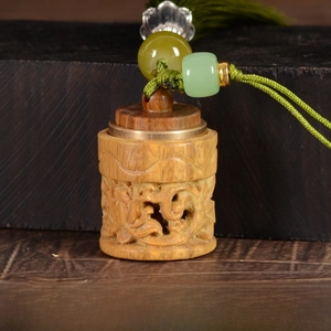 Macro detail of sandalwood cylindrical hollow diffuser pendant with green tassel