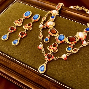 Detailed macro of vintage gold earrings with blue stones and pearls on green velvet