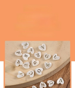 Close-up of 8mm heart-shaped natural freshwater shell beads with gold-engraved letters