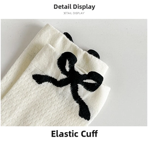 Close-up of white rib-knit sock opening with elastic band and black bow decoration