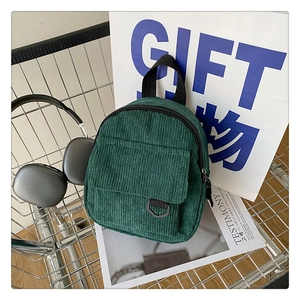 Close-up of retro dark green corduroy mini backpack with D-ring pocket in a shopping cart