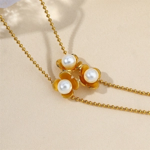 Detailed macro view of 18k gold chain with delicate white pearl flower charms on beige fabric