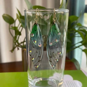 Detailed view of green gradient cicada wing earrings adorned with sparkling rhinestones