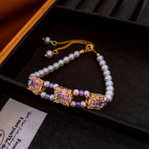 Detail of pearl bracelet featuring purple square zircon stones and gold claw setting