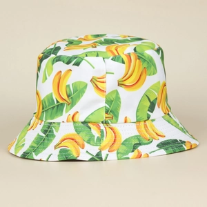 Detailed view of the vibrant banana and green leaf print on the white cotton bucket hat